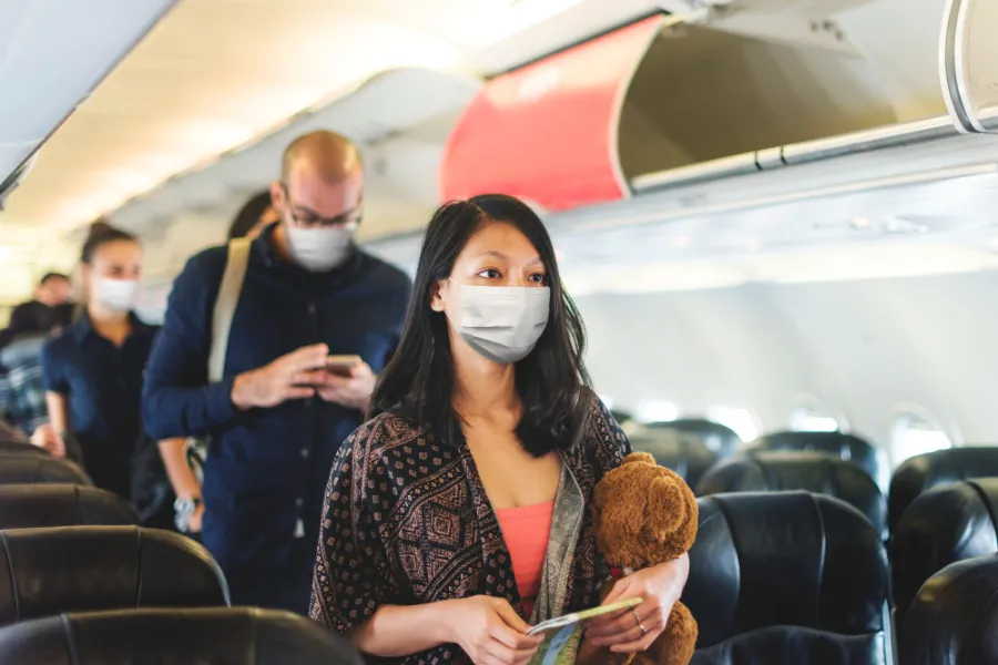 אנשים עם מסיכות פנים על המטוס קונספט הגבלות הבריאות בשדות התעופה 